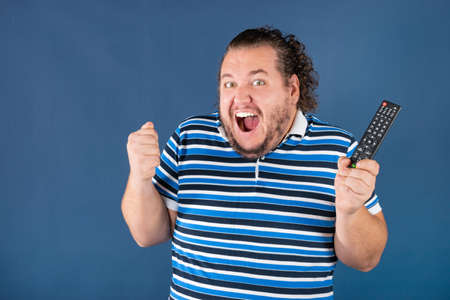 Sports fan with a television remote control. Win or loseの写真素材