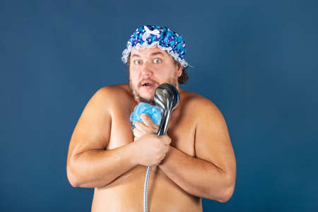 Funny fat man in blue cap sing in the shower. Fun and cleanlinessの写真素材