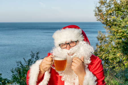 Fat man dressed as Santa drinking beer on the oceanの写真素材