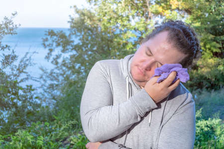 Fat man wipes his face with a towel standing on the oceanの写真素材