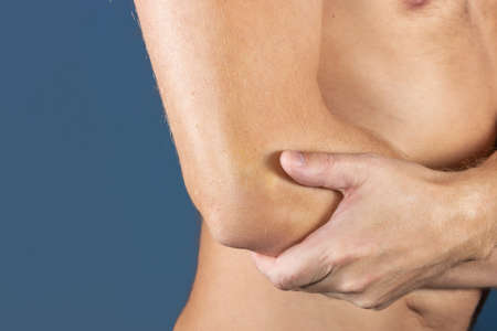 The man holds the elbow due to acute painの写真素材