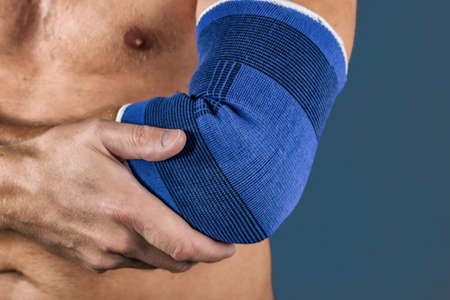 The man holds the elbow due to acute painの写真素材