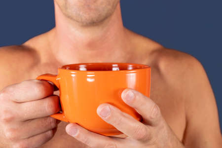 Close up of a hand of man holding a orange coffee cupの写真素材