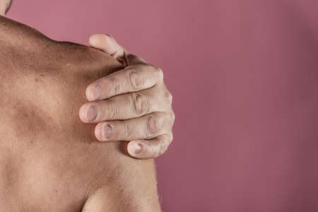 Man holding his sore shoulder trying to relieve painの写真素材