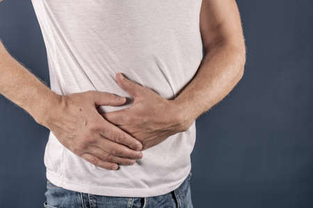 Man suffering from pain in his side. Blue background