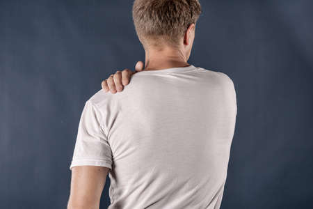 Man holding his sore shoulder trying to relieve painの写真素材