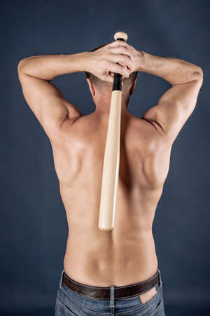 Torso of a shirtless man holding a baseball bat. Vertically framed photographの写真素材
