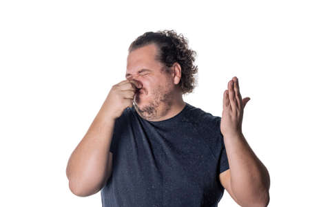 A young man holds or pinches his nose shut because of a stinky smell or odor