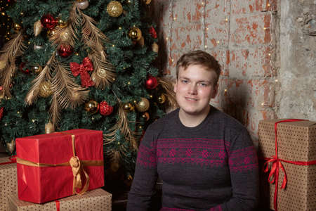 Handsome guy sitting under the tree surrounded by giftsの写真素材