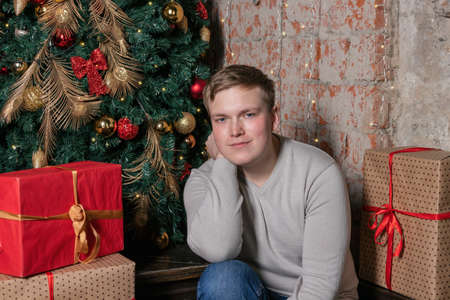 Handsome guy sitting under the tree surrounded by giftsの写真素材