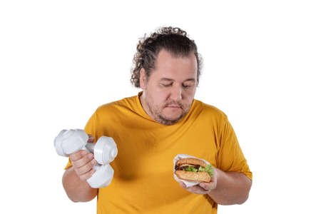 Funny fat man eating unhealthy food and trying to take exercise isolated