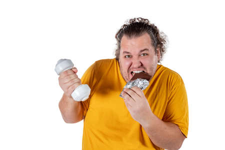 Funny fat man eating unhealthy food and trying to take exercise isolatedの写真素材