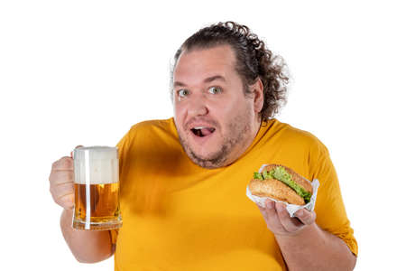 Funny fat man eating burger and drinking alcohol beverageの写真素材