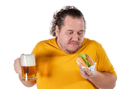 Funny fat man eating burger and drinking alcohol beverageの写真素材