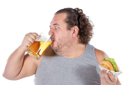 Funny fat man eating burger and drinking alcohol beverageの写真素材