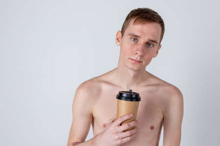 Naked handsome guy drink from coffee or tea cup. Morning refreshment and drinkの写真素材