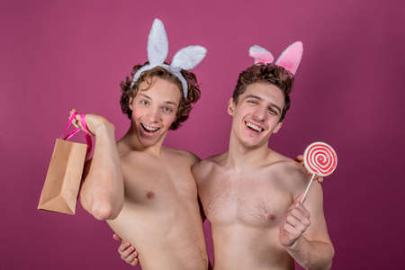 Two funny  wearing bunny ears holding lollipop and big red heartの写真素材