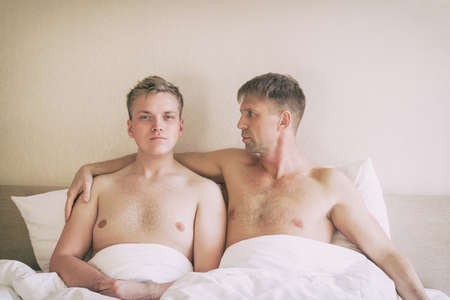 Handsome gay men couple on bed togetherの写真素材