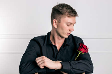 Handsome man wearing black shirt holding a roseの写真素材