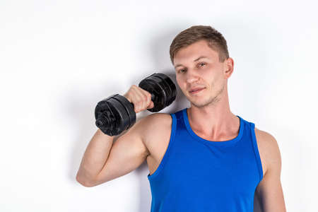 Handsome young man lifting dumbbelの写真素材