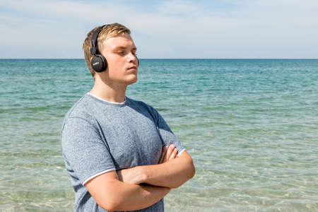 Portrait of a young man on the beach listening to music on headphonesの写真素材