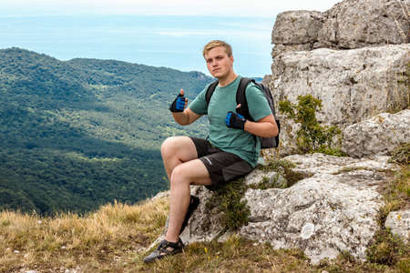 Young man on top of cliff in mountains and enjoying view of natureの写真素材
