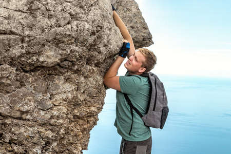 Young man climbing, hanging on edgeの写真素材