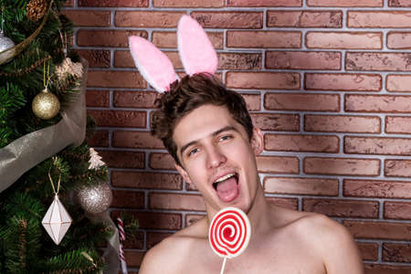 Handsome naked guy in suit rabbit celebrating christmas over brick wallの写真素材