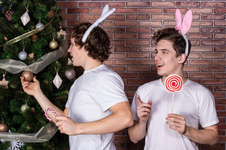 Two funny guys in suits rabbits celebrating christmas over brick wallの写真素材