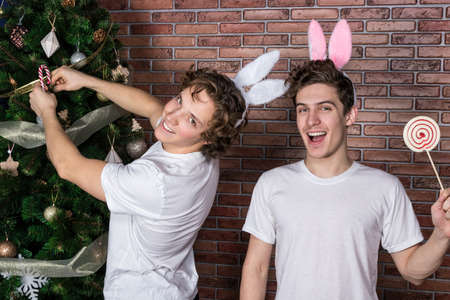 Two funny guys in suits rabbits celebrating christmas over brick wallの写真素材