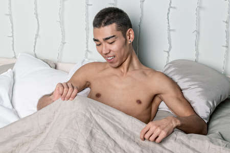Young handsome man rest in bed. Sexy naked guy is resting