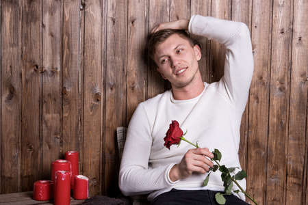 Young handsome man sitting near wood wallの写真素材