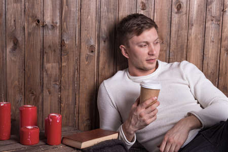 Young handsome man sitting near wood wallの写真素材