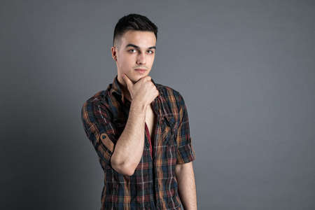 Young serious man posing in studio. Gray backgroundの写真素材