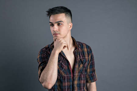 Young serious man posing in studio. Gray background