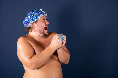 Funny fat man in blue cap sing in the showerの写真素材