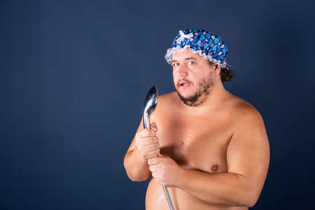 Funny fat man in blue cap sing in the showerの写真素材
