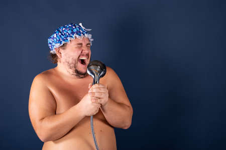 Funny fat man in blue cap sing in the showerの写真素材