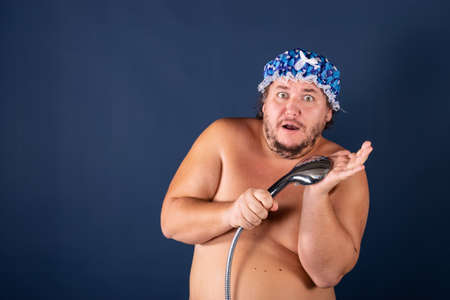 Funny fat man in blue cap sing in the showerの写真素材