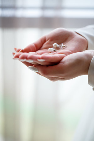 girl in a beautiful white dress holds earrings in her handsの写真素材
