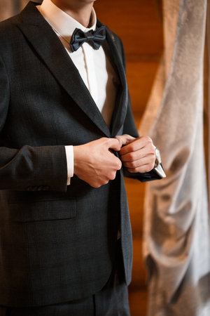 Stylish man groom buttoning a button on his jacketの写真素材