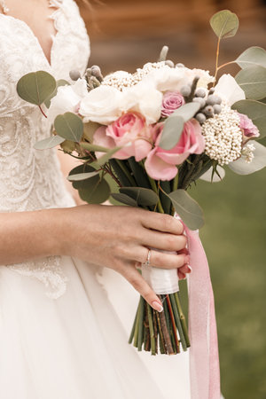 Beautiful bride holding a delicate bouquet of flowers in her hands on a wedding dayの写真素材