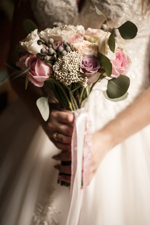 Beautiful bride holding a delicate bouquet of flowers in her hands on a wedding dayの写真素材