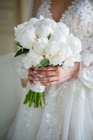 Hands of the bride close-up with a bouquet of fresh beautiful flowers. Attribute of the brideの写真素材