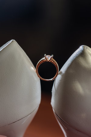 Gold ring of the bride with a pebble between white shoes with heels. Bride's precious ringの写真素材
