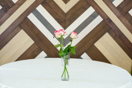 pink roses in a transparent vase on a tableclothの写真素材