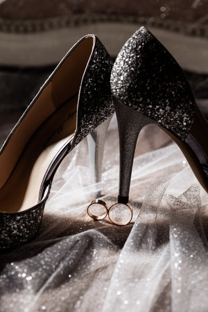 Golden rings of the newlyweds between white shoes with heels. Precious rings of the bride and groomの写真素材