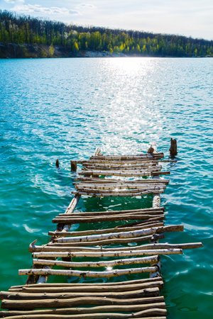 Wooden masonry stands on the water isolated. Entry into the lake from a wooden bridge into the lakeの写真素材