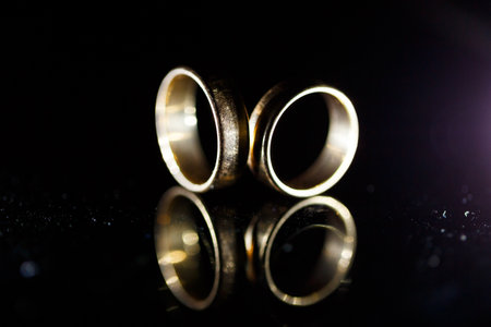 Gold wedding ring on black glassの写真素材