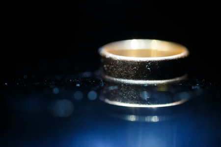 Gold wedding ring on black glassの写真素材